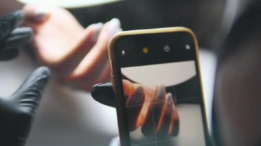 Manikürün sonu, telefon kamerasındaki çivilerin fotoğrafını çekmek.