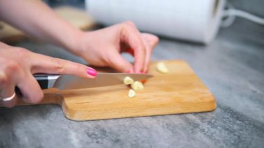 Tahtada sarımsak kesen bir kadın.