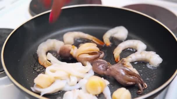 Egy nő tengeri koktélt tesz egy serpenyőbe. — Stock videók