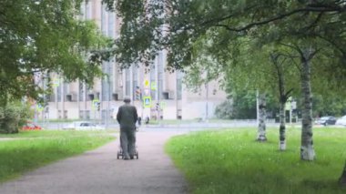 Parkta bebek arabasıyla yürüyen bir adam