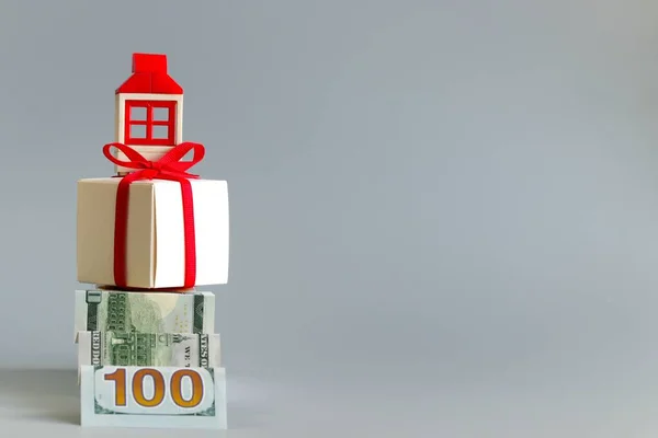Yüz dolarlık banknottan yapılmış bir merdiven kırmızı kurdeleli bir kutuya ve bir evi temsil eden bir figürle bağlanır. Hayalindeki evi satın alma ve kurtarma kavramı. Boş alan