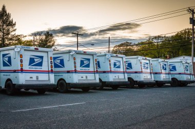 Parlin, NJ - 5/20: A number parked United States Postal Services vans in front of a Post Office clipart
