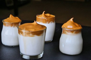 Köpüklü Dalgona kahvesi. Kırbaçlanmış ya da dövülmüş kahveden yapılmış bulanık siyah arka planda