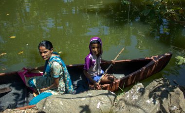 Allepey, Hindistan - 11 Mart 2014: Annesiyle birlikte Hindistan 'ın güney kesimindeki Kerala' nın en turistik durgun vadisinde özel teknelerinde seyahat eden bir çocuk