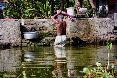 Elbiselerini geleneksel bir şekilde yıkayan bir adam Hindistan 'ın güneyindeki Kerala eyaletinde yer alan Allepey' de küçük bir köyde.