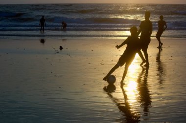 Çocuklar Goa, Hindistan 'da güzel bir plajda gün batımında futbol oynuyorlar.