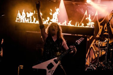 Krakow, Polonya - 20 Eylül 2014: Arkaplanda gitar ve alevlerle rock thrash metal müzik yapan bir adamın soyutlanması.