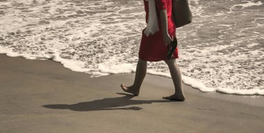 Hindistan, Kerala 'da deniz kıyısında yalınayak yürüyen bir kız ve dalgalar..