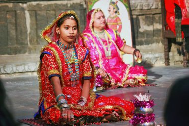 Udaipur, Hindistan - 24 Mayıs 2013: Sari giymiş iki Hintli kadın yerde otururken dans ediyorlar