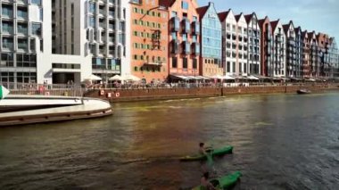 Gdansk, Kuzey Polonya - 15 Ağustos 2020: Motlawa nehrinde kayak yapmak gibi boş aktiviteler yapan insanlar hafta sonu şehir merkezinin ana meydanında gün batımında
