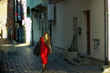 Gdansk, Kuzey Polonya - 15 Ağustos 2020: Kırmızı elbiseli bir kadın eski şehir merkezinde gündüz vakti sokak geçidinde yürüyor