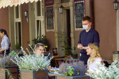 Gdansk, Kuzey Polonya - 15 Ağustos 2020: Bir restoranda garsonluk yapan ve 19 Ağustos 'ta koruyucu maske takarak geçinen bir erkek garson