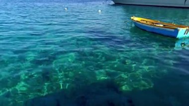 Kristal berrak mavi suyun üzerinde yüzen renkli bir tekne Yunanistan 'daki Halki (Chalki) kırsal, tepe adasında