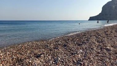 Rodos, Yunanistan: Akdeniz 'de gündüz vakti yüzen insanlarla birlikte rodos adasının sahilinde dalgaların durağan görüntüsü