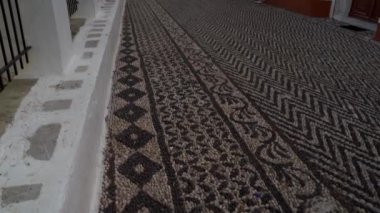 Symi, Yunanistan - 25 Eylül 2020: Akdeniz kıyısındaki ortaçağ kilisesinin yanında yer ve turistin üzerine oyulmuş Yunan tasarımı. Sınıflandırılmamış / düz çalışma profili.