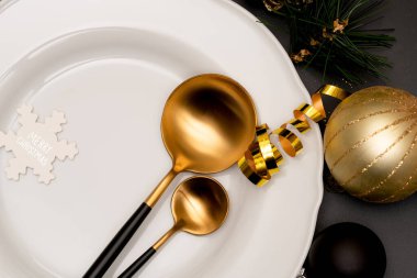 Altın çatal bıçaklı ve beyaz tabaklı Noel masası.