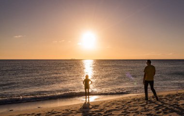 Gün batımında sahilde yürüyen iki genç kadın.