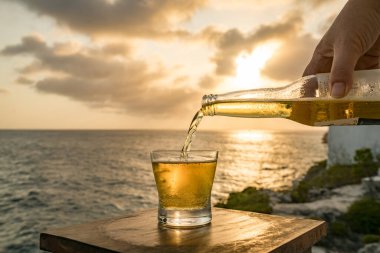Günbatımında, Curacao Okyanusu 'nun kıyısında içiyor.