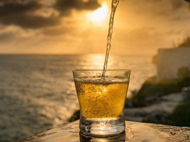 Günbatımında, Curacao Okyanusu 'nun kıyısında içiyor.