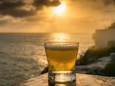 Günbatımında, Curacao Okyanusu 'nun kıyısında içiyor.