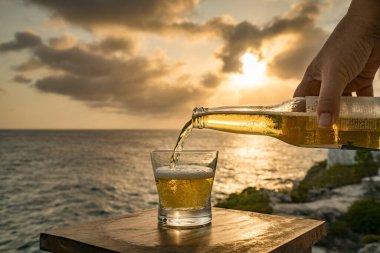 Günbatımında, Curacao Okyanusu 'nun kıyısında içiyor.