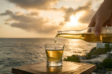 Günbatımında, Curacao Okyanusu 'nun kıyısında içiyor.
