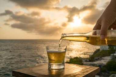 Günbatımında, Curacao Okyanusu 'nun kıyısında içiyor.