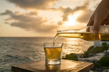 Günbatımında, Curacao Okyanusu 'nun kıyısında içiyor.