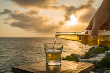 Günbatımında, Curacao Okyanusu 'nun kıyısında içiyor.