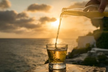 Günbatımında, Curacao Okyanusu 'nun kıyısında içiyor.