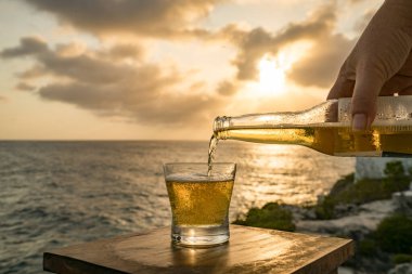 Günbatımında, Curacao Okyanusu 'nun kıyısında içiyor.