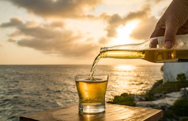 Günbatımında, Curacao Okyanusu 'nun kıyısında içiyor.