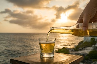 Günbatımında, Curacao Okyanusu 'nun kıyısında içiyor.