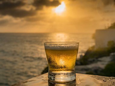 Günbatımında, Curacao Okyanusu 'nun kıyısında içiyor.