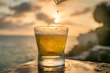 Günbatımında, Curacao Okyanusu 'nun kıyısında içiyor.