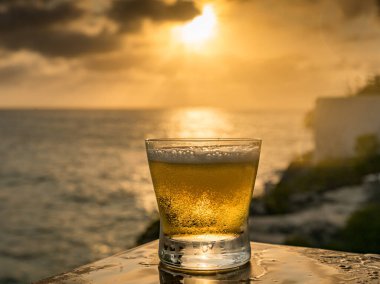 Günbatımında, Curacao Okyanusu 'nun kıyısında içiyor.