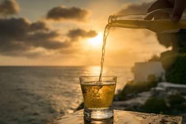 Günbatımında, Curacao Okyanusu 'nun kıyısında içiyor.