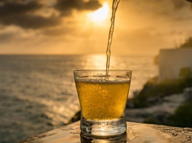 Günbatımında, Curacao Okyanusu 'nun kıyısında içiyor.