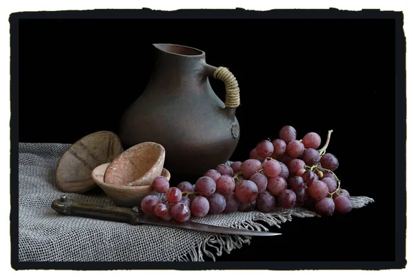 Retro style kitchen still life with knife, grape, pitcher, dishes.