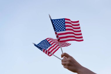 Mavi gökyüzünde Amerikan bayrağı sallayan kadın eli. İzole. Amerika. ABD. Kavram. 4 Temmuz ABD.