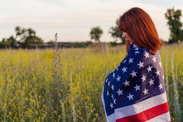 Young excited woman with the United States flag enjoying sunset in nature. July 4 independence day of the united states