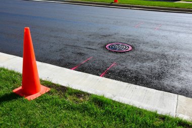 Kanalizasyon kapakları etrafında işaretler olan asfalt kaplamasına hazırlanmak makine operatörlerine yeni çalışmalara zarar vermekten kaçınmaları gereken noktayı bildirmek. 