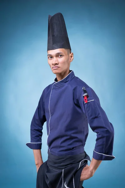 Mavi Üniformalı Siyah Önlüklü Mavi Arka Planda Siyah Şapkalı Asyalı — Stok fotoğraf