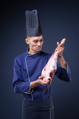 Mavi üniformalı, siyah önlüklü ve gri arka planda siyah şapkalı bir Asyalı yönetici şefin portresi.