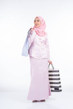 Beyaz arka planda izole edilmiş alışveriş torbaları taşıyan, Asyalı geleneksel elbiseli güzel bir Müslüman kadın manken. Idul fitri festival hazırlık alışveriş konsepti. Tam boy portre.