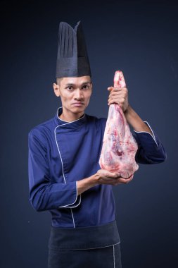 Mavi üniformalı, siyah önlüklü ve gri arka planda siyah şapkalı bir Asyalı yönetici şefin portresi.