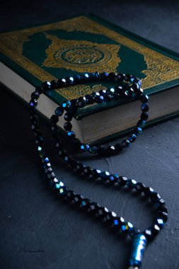 İslam kavramına olan inanç. İslam kutsal kitabı Kuran ya da Kuran 'da tespih boncukları ya da koyu arkaplanda tasbih..