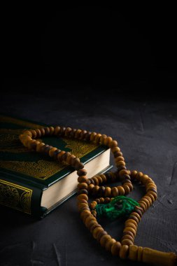 İslam kavramına olan inanç. İslam kutsal kitabı Kuran ya da Kuran 'da tespih boncukları ya da koyu arkaplanda tasbih..