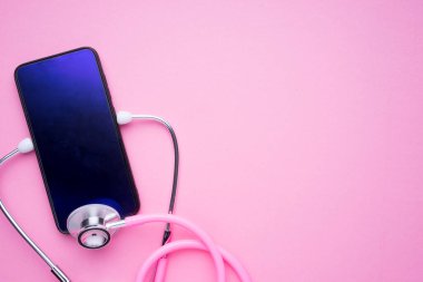 Kadın sağlık hizmetleri konsepti teknolojisi. Pembe bir steteskop ve pembe arka planda bir akıllı telefon. Peyzaj yönelimi.