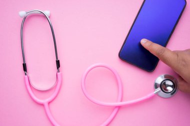 Kadın sağlık hizmetleri konsepti teknolojisi. Pembe bir steteskop ve pembe arka planda bir akıllı telefon. Peyzaj yönelimi.